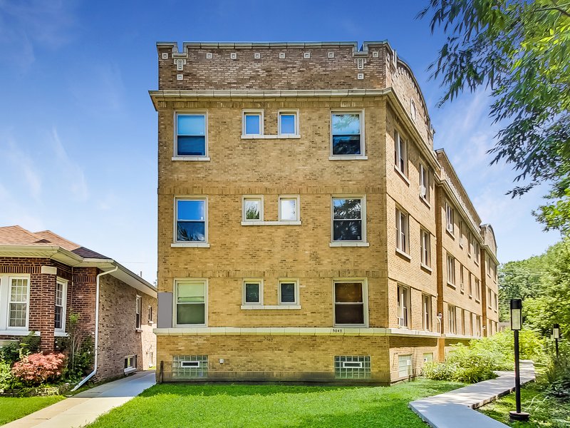 Three-story brick walk-up with a front lawn